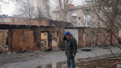 A local resident stands near buildings damaged by a Russian military strike in Bakhmut