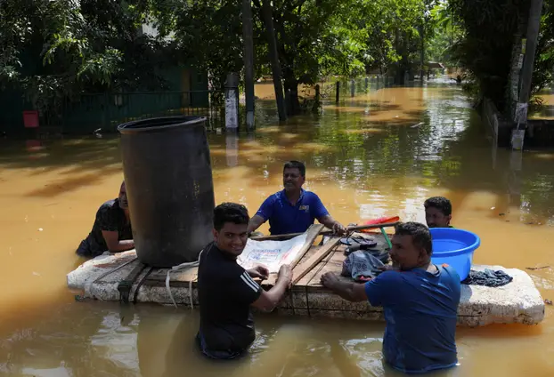 People hold on to a makeshift raft at a flooded area, following Cyclone Ditwah in Kelaniya
