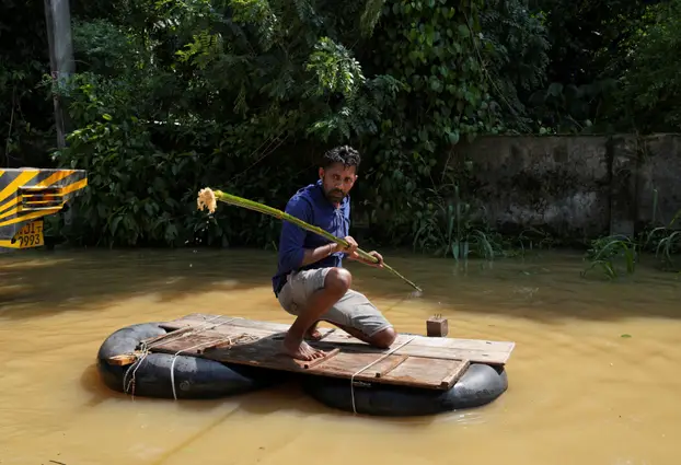 A man uses a makeshift raft at a flooded area, following Cyclone Ditwah in Kelaniya