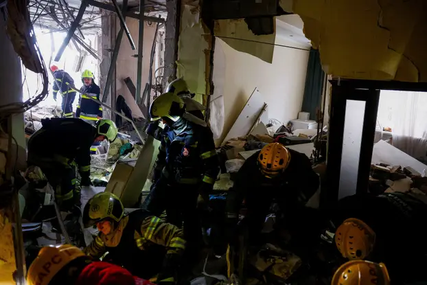 Firefighters work at the site of an apartment building hit during Russian missile and drone strikes, amid Russia’s attack on Ukraine in Kyiv