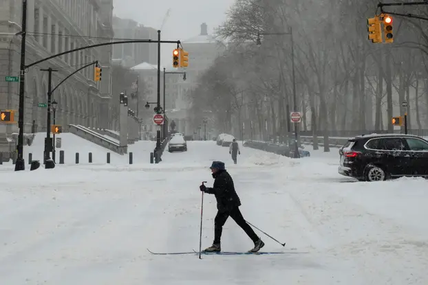 A person on skis walks amid a major winter storm spreading across a large swath of the United States, in Brooklyn