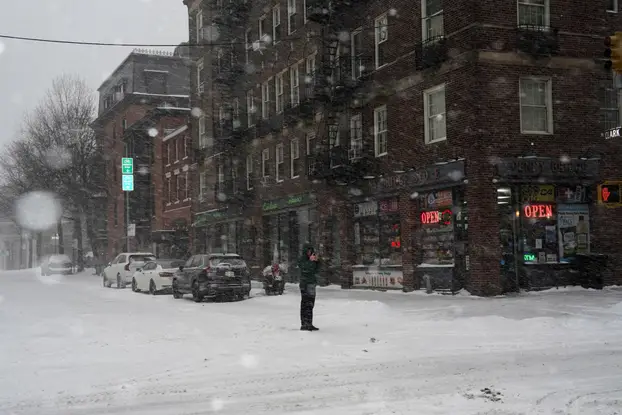 FILE PHOTO: A pedestrian uses his mobile phone to photograph snowfall, in Brooklyn